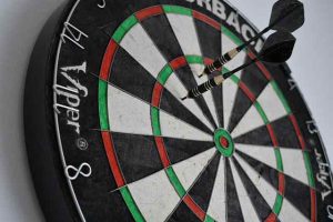 A dartboard with two darts in different areas illlustrating a difference between geo-targeting and geo-fencing.